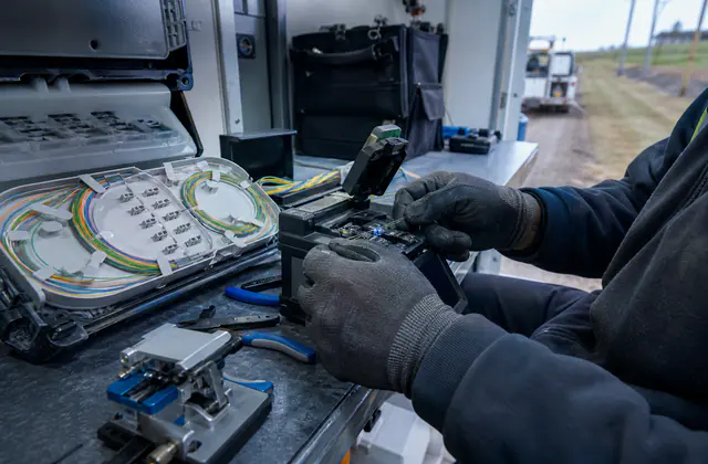 Technician aligning fibre optic strands in a fusion splicer